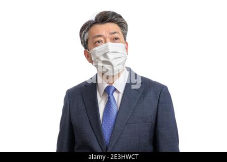 Portrait d'un homme d'affaires asiatique d'âge moyen portant un masque blanc. Arrière-plan blanc. Covid19, concepts de santé et d'affaires. Banque D'Images