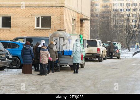 Saint-Pétersbourg, Russie - 09 janvier 2021: File d'attente composée de femmes signifie lait de ferme dans une citerne dans la cour d'un quartier résidentiel Banque D'Images