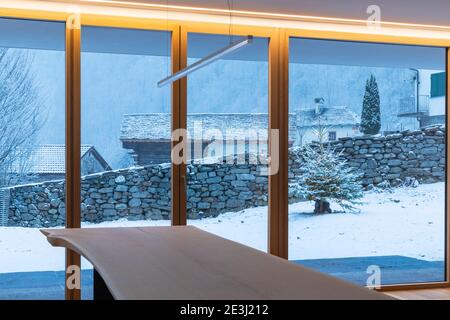 Intérieur d'une salle à manger, avec une grande baie vitrée, personne à l'intérieur et à l'extérieur il y a de la neige Banque D'Images