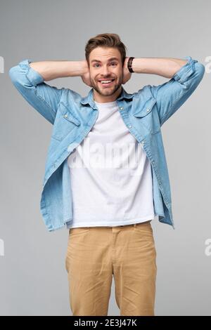 jeune homme avec les oreilles fermées debout sur fond gris studio Banque D'Images