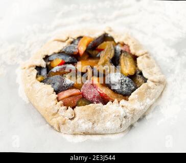 La tarte aux prunes est prête pour la cuisson. Prunes mûres en pâte à croûte courte. Faire cuire des biscuits et de la farine blanche. Banque D'Images