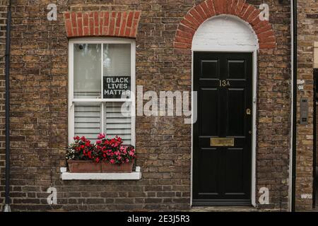 Entrée de la maison avec une porte noire et un panneau Black Lives Matter sur la fenêtre. Une rue à Windsor, Berkshire, Angleterre, Royaume-Uni. Banque D'Images