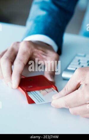 gros plan d'un jeune homme caucasien, portant un élégant costume bleu, à la réception, en insérant une identification électronique dans un lecteur rouge Banque D'Images