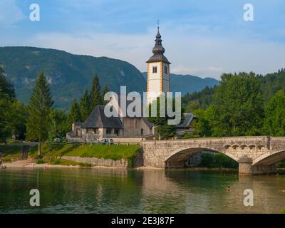 Clocher de l'église et le pont de pierre, à lac de Bohinj dans Ribicev village alpin Laz, Slovénie Banque D'Images