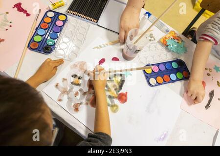 Concours de dessin de Noël pour enfants. Enfants peignant des bonhommes de neige gris. Boîte de peinture à l'eau et boîte d'étoiles auto-adhésives Banque D'Images