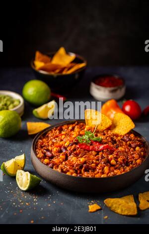 Chili chaud mexicain con carne dans un bol avec tortilla jetons sur fond sombre Banque D'Images
