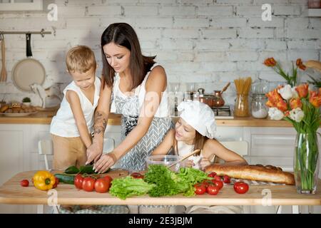 Maman cuisine le déjeuner avec les enfants. Une femme enseigne à sa fille la cuisine de son fils. Végétarisme et alimentation naturelle saine Banque D'Images