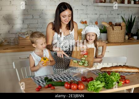 Maman cuisine le déjeuner avec les enfants. Une femme enseigne à sa fille la cuisine de son fils. Végétarisme et alimentation naturelle saine Banque D'Images