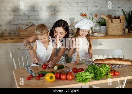 Maman cuisine le déjeuner avec les enfants. Une femme enseigne à sa fille la cuisine de son fils. Végétarisme et alimentation naturelle saine Banque D'Images