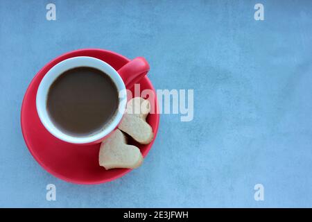 Tasse de café rouge et biscuits en forme de coeur sur fond de béton gris. Banque D'Images