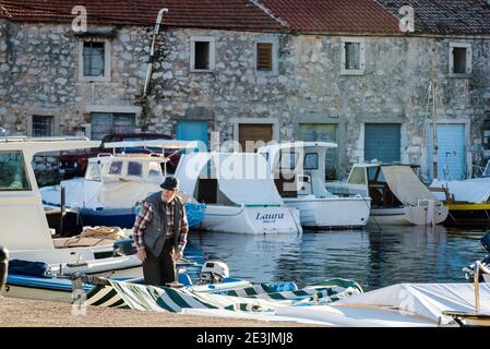 Homme dans son bateau, Port au Mali Iz, sland d'Iz, archipel de Zadar, Dalmatie, Croatie Banque D'Images