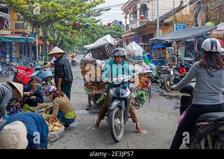 Femme vietnamienne à moto lourdement chargée de poulets pour le marché dans la ville de Hoi an / Fai-fo / Faifoo, province de Quảng Nam, centre du Vietnam Banque D'Images
