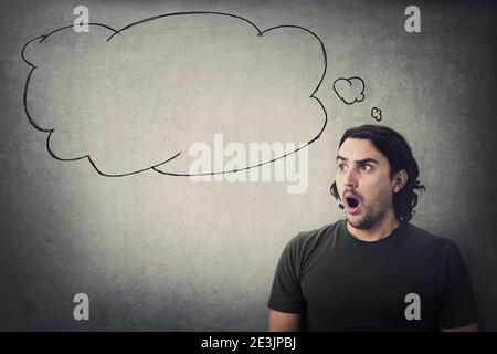 Homme étourdi et choqué, les yeux grands regarde de côté étonnés et une bulle de pensée vide sort de sa tête. Un gars stupéfait avec une étoile d'expression à bouche ouverte Banque D'Images