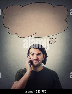 Un homme frustré au cours d'une conversation téléphonique, fait une expression insatisfaite. Bulle de pensée vide, nuage de réflexion, au-dessus de sa tête. Le gars a déçu Banque D'Images