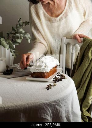 Livre gâteau, femme fait la décoration avec glaçage blanc, la vie moderne encore sur la table blanche et chaise blanche. Eucalyptus Banque D'Images