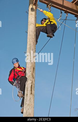 deux hommes travaillant sur un poteau en bois à l'entraînement de corde élevée exercice Banque D'Images