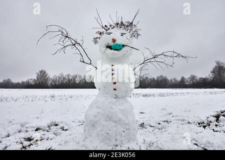 Bonhomme de neige en paysage hivernal portant un masque facial pour la protection et le confinement du coronavirus, Covid-19 Banque D'Images