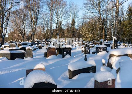 La neige couvrait les pierres de tête et les tombes lors d'une journée d'hiver ensoleillée au cimetière Hietaniemi d'Helsinki, en Finlande Banque D'Images