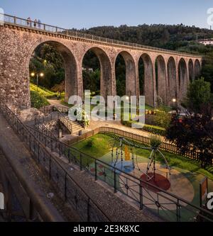 Paysage du Parque da Liberdade à Vouzela, Portugal, avec l'ancien pont ferroviaire mis en évidence et l'aire de jeux en premier plan. Banque D'Images