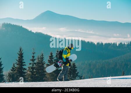 homme marchant sur une colline avec des montagnes de surf des neiges en arrière-plan Banque D'Images