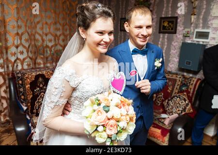 une jeune mariée embrasse et embrasse le marié à l'intérieur de la maison, rencontrant les amoureux élégants des jeunes mariés avant la cérémonie de mariage Banque D'Images