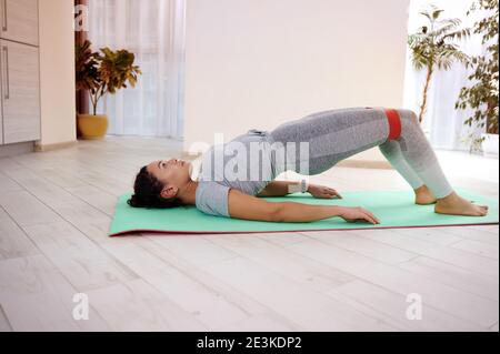 Un jeune athlète effectue un pont de jute sur un tapis de fitness. Concept d'entraînement à domicile Banque D'Images