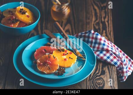 Dessert à l'orange avec miel au vin ou sirop d'érable et épices au gingembre, baies de grenade décorées dans une assiette bleue. Des aliments merveilleusement sucrés, riches et frais. D Banque D'Images