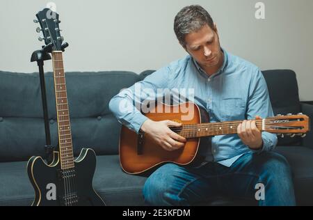 Beau homme jouant de la guitare espagnole à la maison. Banque D'Images