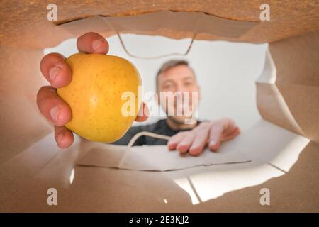 Homme prenant la pomme du sac de papier d'épicerie. Livraison à domicile à l'épicerie Banque D'Images