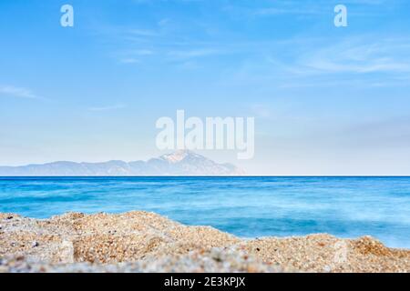 Plage de Sarti, Sithonia, Chalkidiki, Grèce ; vue sur le Mont Athos au-dessus de la plage de sable et de l'eau de mer calme ; paysage marin en fin d'après-midi Banque D'Images