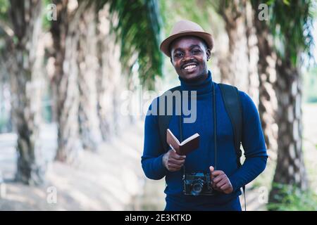 Homme de voyage africain tenant l'appareil photo et le passeport avec le sourire et heureux Banque D'Images