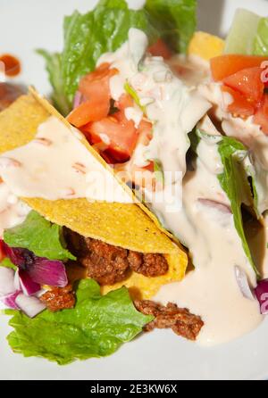 Tacos de bœuf haché et salade de laitue romaine, tomates en dés et oignons violets coupés en dés sur une assiette blanche Banque D'Images