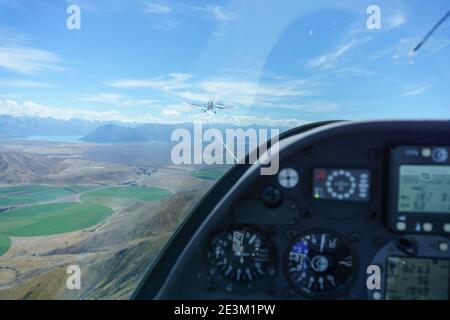 Vue floue à travers la voûte en perspex depuis le poste de pilotage du planeur lorsqu'il est remorqué depuis un avion de remorquage au-dessus du paysage de Canterbury en Nouvelle-Zélande. Banque D'Images
