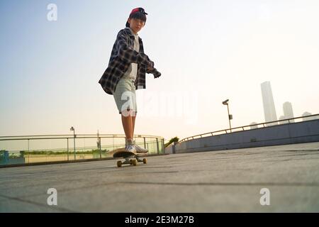 enfant asiatique adolescent skate à l'extérieur sur un pont piétonnier Banque D'Images