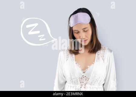 Femme asiatique en robe de nuit en satin portant robe de chambre blanche en dentelle dormir debout parce que endormi. Personnes souffrant de somnambulisme. Ajoutez un espace gris sur la lef Banque D'Images