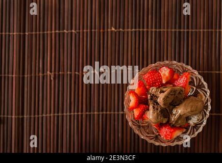 Fraises et glace au chocolat dans un bol en cristal un tapis de bambou Banque D'Images