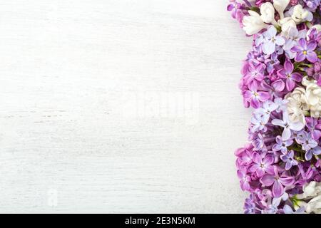 Différentes petites fleurs de lilas sur fond blanc en bois. Bordure fleurie. Pose à plat. Banque D'Images
