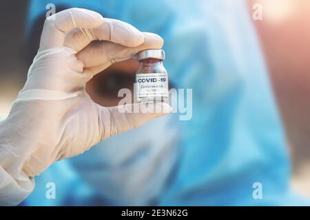 Jeune femme médecin portant un masque de protection PPE et des gants portant une seringue et un vaccin contre le coronavirus. Le concept d'un nouveau vaccin contre la maladie, la grippe Banque D'Images