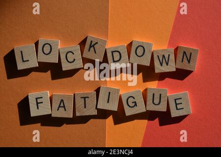 Fatigue de verrouillage, mots en lettres d'alphabet en bois isolées sur fond rouge et orange Banque D'Images