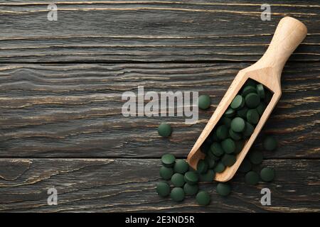 Pelle en bois avec des pilules de spiruline sur fond en bois, espace pour le texte Banque D'Images