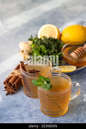 Deux tasses de thé chaud avec herbes, épices, citron, racine de gingembre et miel, fond de pierre bleue. Tisane à la menthe et au thym. Mise au point sélective. Banque D'Images