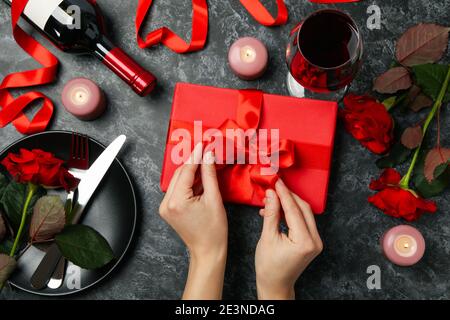 Femme déballant une boîte cadeau sur noir avec des accessoires pour la Journée de la femme, une surprise cadeau pour la Journée de la femme dans un flat lay pour la Journée de la femme Banque D'Images