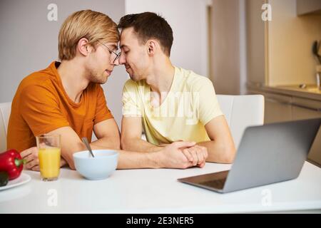 Couple gay heureux tenant les mains et touchant les fronts Banque D'Images