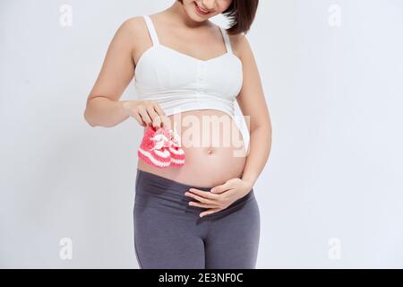 Un portrait d'une femme enceinte avec une paire de chaussures bébé en tricot rose Banque D'Images