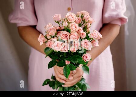 femme mains tenant bouquet de roses roses roses avec robe rose. lumière naturelle. concept de saison de printemps. lumière douce. roses roses en fleur Banque D'Images