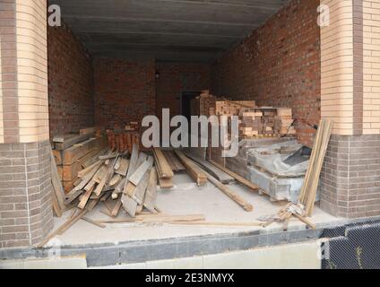 Le stockage de matériaux de construction tels que des briques, des planches en bois, des chevrons, et des poutres de toit à l'intérieur du garage de maison inachevé en construction. Banque D'Images
