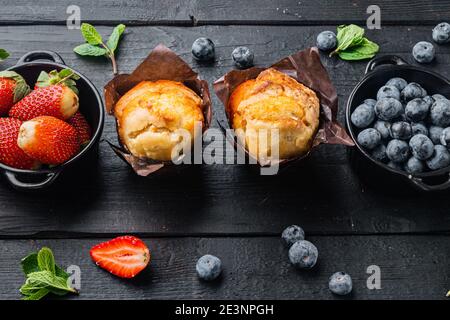 Muffins aux myrtilles avec berrie fraîche, sur fond de table en bois noir Banque D'Images