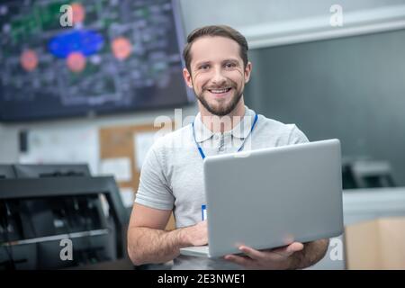 Beau homme debout avec un ordinateur portable ouvert à l'intérieur Banque D'Images