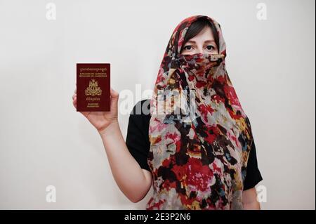La jeune femme musulmane arabe en vêtements hijab tient le passeport du Royaume du Cambodge sur fond de mur blanc, portrait de studio. Banque D'Images