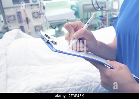 Une travailleuse de la santé écrit quelques notes dans la salle d'hôpital. Banque D'Images